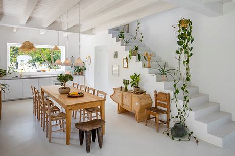 A modern, rustic interior with wooden furniture, plants, and a staircase.