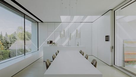 Minimalist dining room with white cabinetry, long table, and pendant lighting.