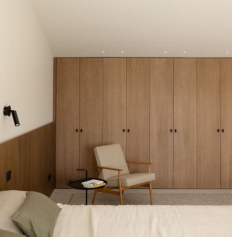 Minimalist bedroom with wood-paneled walls, modern armchair, and minimal decor.
