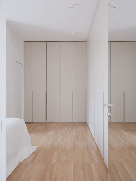 A minimalist bedroom with built-in closets and hardwood floors, showcasing clean lines and neutral tones.