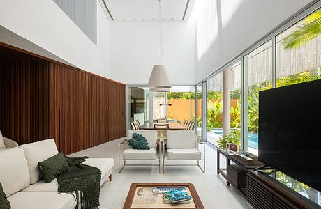 Sleek modern interior with high ceilings, glass walls, and tropical garden views.