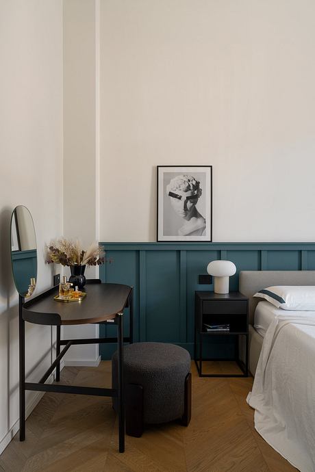 Minimalist bedroom with teal accent wall, black furniture, and framed artwork.