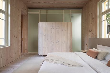 Cozy, rustic bedroom with wooden walls, minimalist furnishings, and large built-in closet.