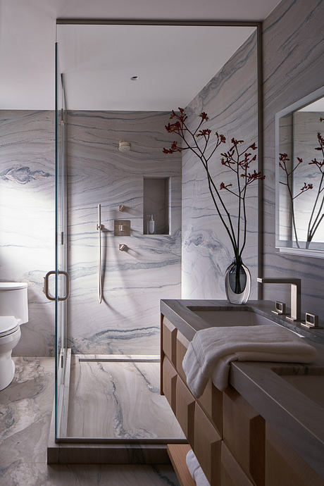 Modern bathroom with elegant marble walls, sleek vanity, and artful floral display.