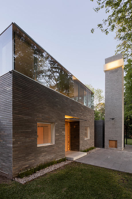 Sleek modern design with large glass windows, dark wooden panels, and a prominent chimney.