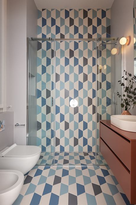 Stylish bathroom with geometric tile pattern walls and sleek glass shower enclosure.