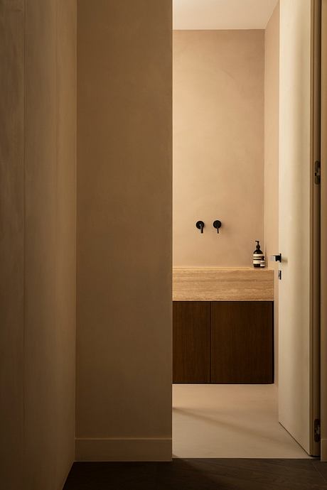 A minimalist bathroom with a wooden vanity, black fixtures, and clean lines.