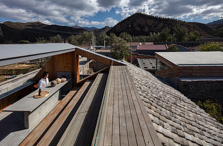 Wooden deck with bench overlooking mountainous landscape and rooftops.