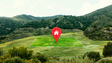 Rolling green hills with a large red location marker icon in the foreground.