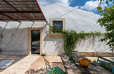 Rustic exterior with thatched roof, concrete window frame, and lush greenery surroundings.