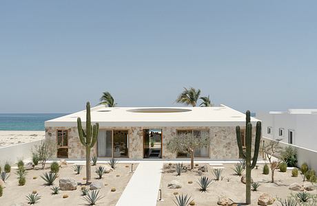 Modern desert-style home with stone facade, cactus landscaping, and ocean view.