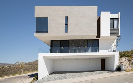 A modern, minimalist house with concrete, glass, and stone facade, featuring clean lines and a open layout.