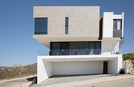 A modern, minimalist house with concrete, glass, and stone facade, featuring clean lines and a open layout.