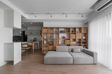 Minimalist open-plan living space with modular shelving, sofa, and dining area.