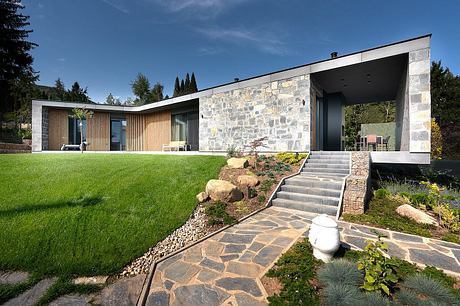 A modern, stone-clad home with a spacious outdoor patio and a well-landscaped yard.