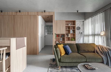 A modern, minimalist living space with wood paneling, built-in shelving, and a cozy sofa.