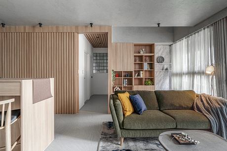 A modern, minimalist living space with wood paneling, built-in shelving, and a cozy sofa.