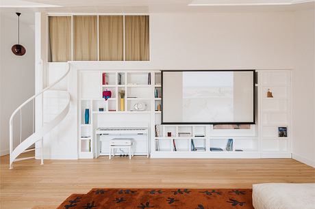 A modern, minimalist living room with a large TV, built-in shelves, and a spiral staircase.