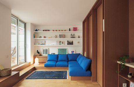 Sleek modern living room with blue sectional sofa, floating shelves, and wood accents.