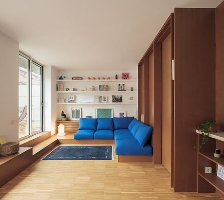 Sleek modern living room with blue sectional sofa, floating shelves, and wood accents.