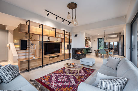 Modern living room with wooden shelving unit, track lighting, and cozy fireplace.