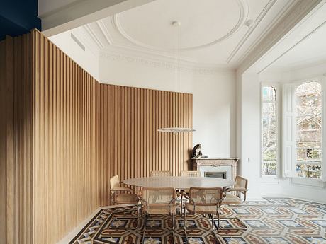 Elegant dining room with ornate ceiling, wooden paneled walls, and patterned tile flooring.