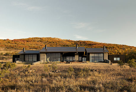 A contemporary desert retreat with sleek black exteriors and large windows offering panoramic views.