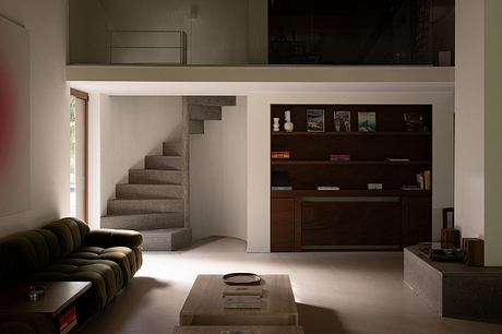 A modern living room with concrete stairs, dark wood shelves, and a cushioned sofa.