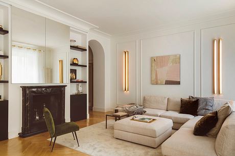Elegant, modern living room with neutral tones, artful lighting, and antique fireplace.
