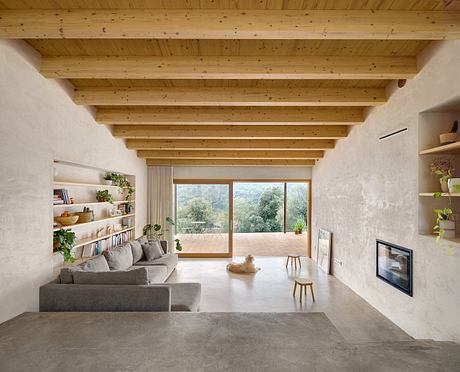 Cozy wood-beamed ceiling, exposed concrete floors, and sliding glass doors open to nature.