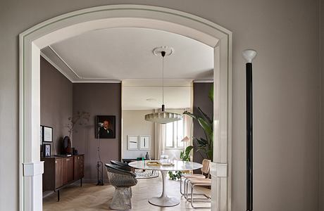 Elegant arched entryway leads to a stylish modern dining area with marble table.