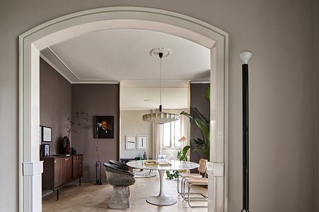 Elegant arched entryway leads to a stylish modern dining area with marble table.