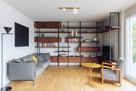Cozy modern living room with wooden shelving, gray sofa, and yellow accent chair.