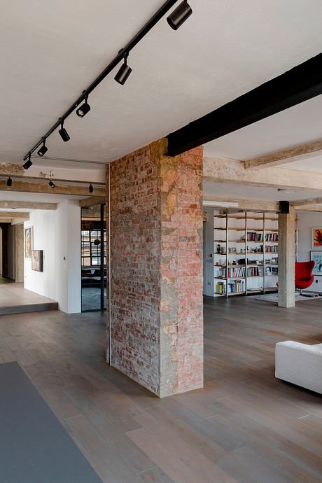An open-concept loft space featuring exposed brick walls, industrial lighting, and wooden beams.