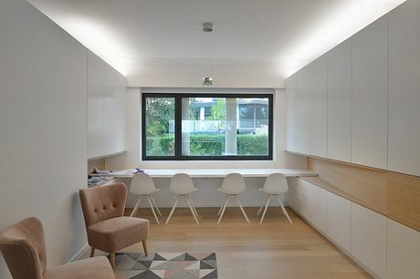 Modern, minimalist room with large window, built-in workspace, and stylish chairs.