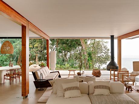 Spacious open-concept living space with wooden beams, large windows, and lush outdoor views.