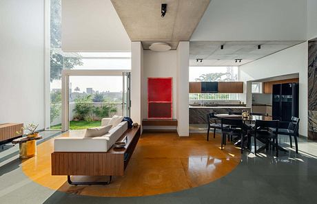 Spacious, modern living room with sleek furniture, large windows, and striking red artwork.