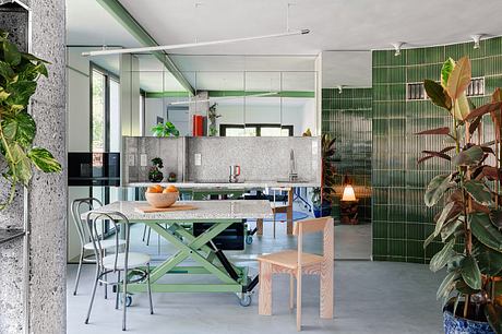 Modern open-concept kitchen and dining area with green accents, concrete surfaces, and natural light.