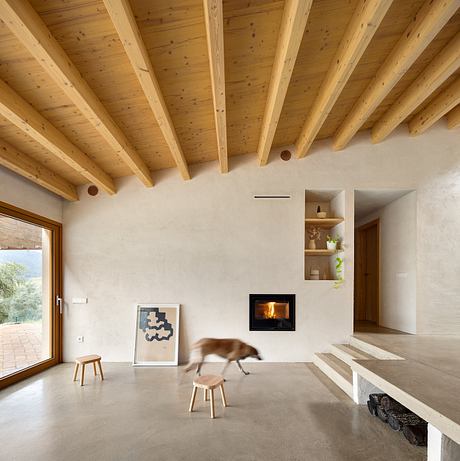 Spacious room with wooden beamed ceilings, concrete floor, and minimalist furnishings.