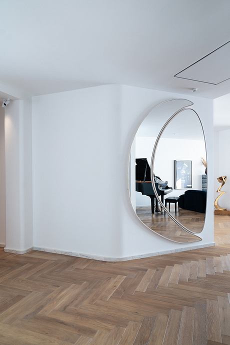Elegant interior with curved mirror, hardwood flooring, and minimalist furnishings.