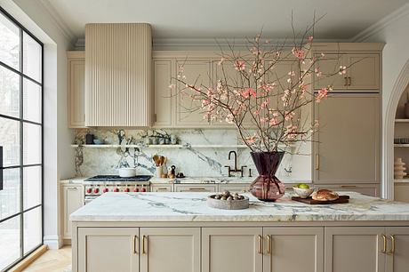 Elegant kitchen featuring marble countertops, wood cabinetry, and a striking floral centerpiece.