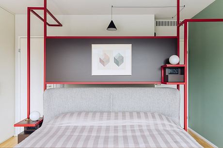 Modern, minimalist bedroom design with red metal accents, geometric artwork, and striped bedding.