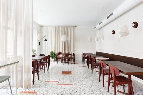 A modern dining space with sleek furniture, white walls, and pendant lighting.