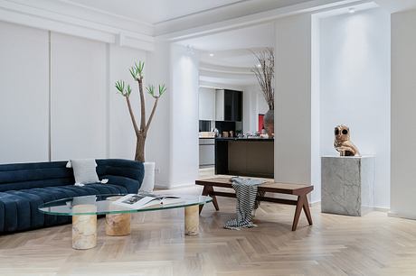 Minimal, modern living room with navy sofa, glass coffee table, and sculptural decor.
