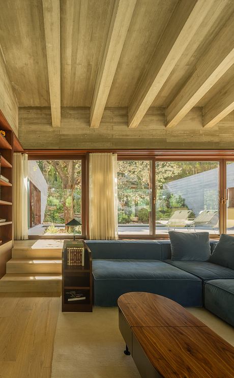 Rustic wooden beams and large windows overlook a lush outdoor garden scene.