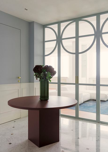 A modern entryway with arched windows, a circular dark wood table, and a potted plant.