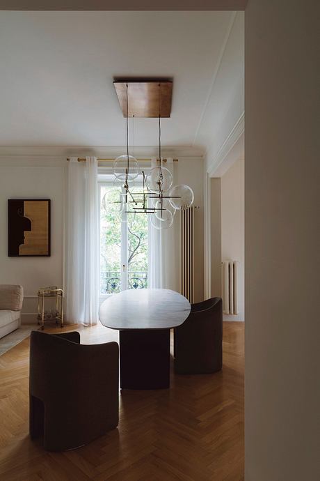 A modern interior with a statement light fixture, wood flooring, and minimalist furniture.