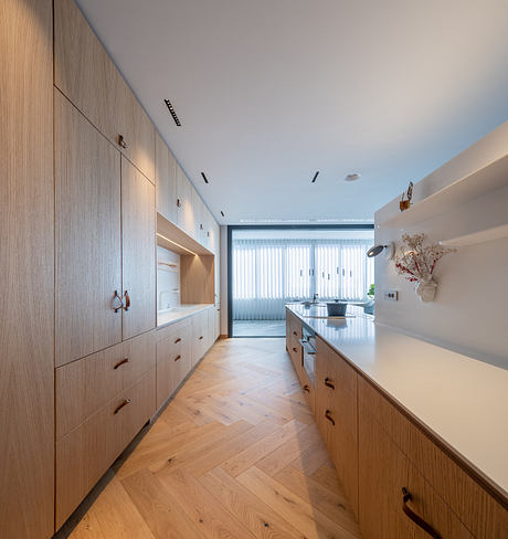 Sleek modern kitchen with wood cabinets, herringbone floor, and large sliding window.