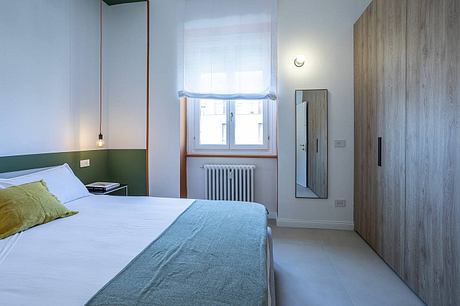 Calm, minimalist bedroom with wood paneling, white walls, and a cozy bed.