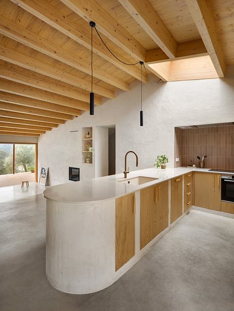 Minimalist kitchen with curved counter, wooden beams, and pendant lighting.